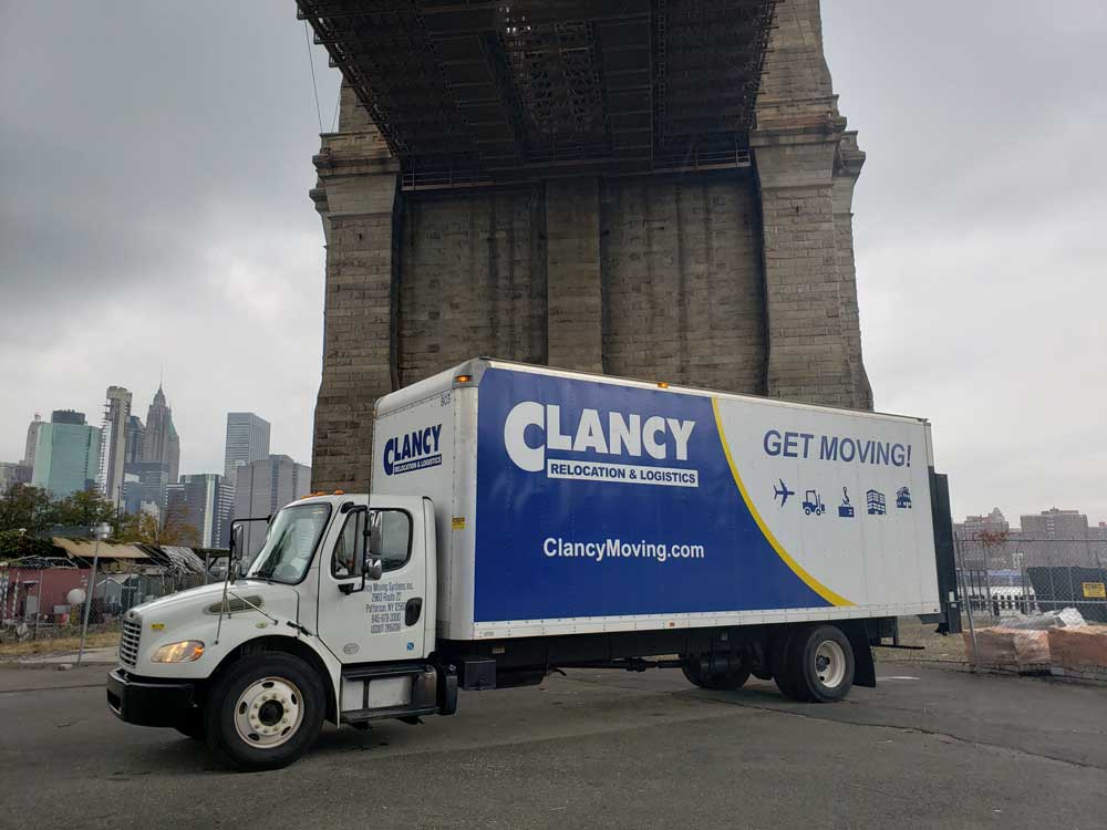 A Clancy moving truck parked under the Brooklyn Bridge.