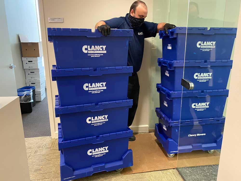 A person moving a blue storage box on top of each other